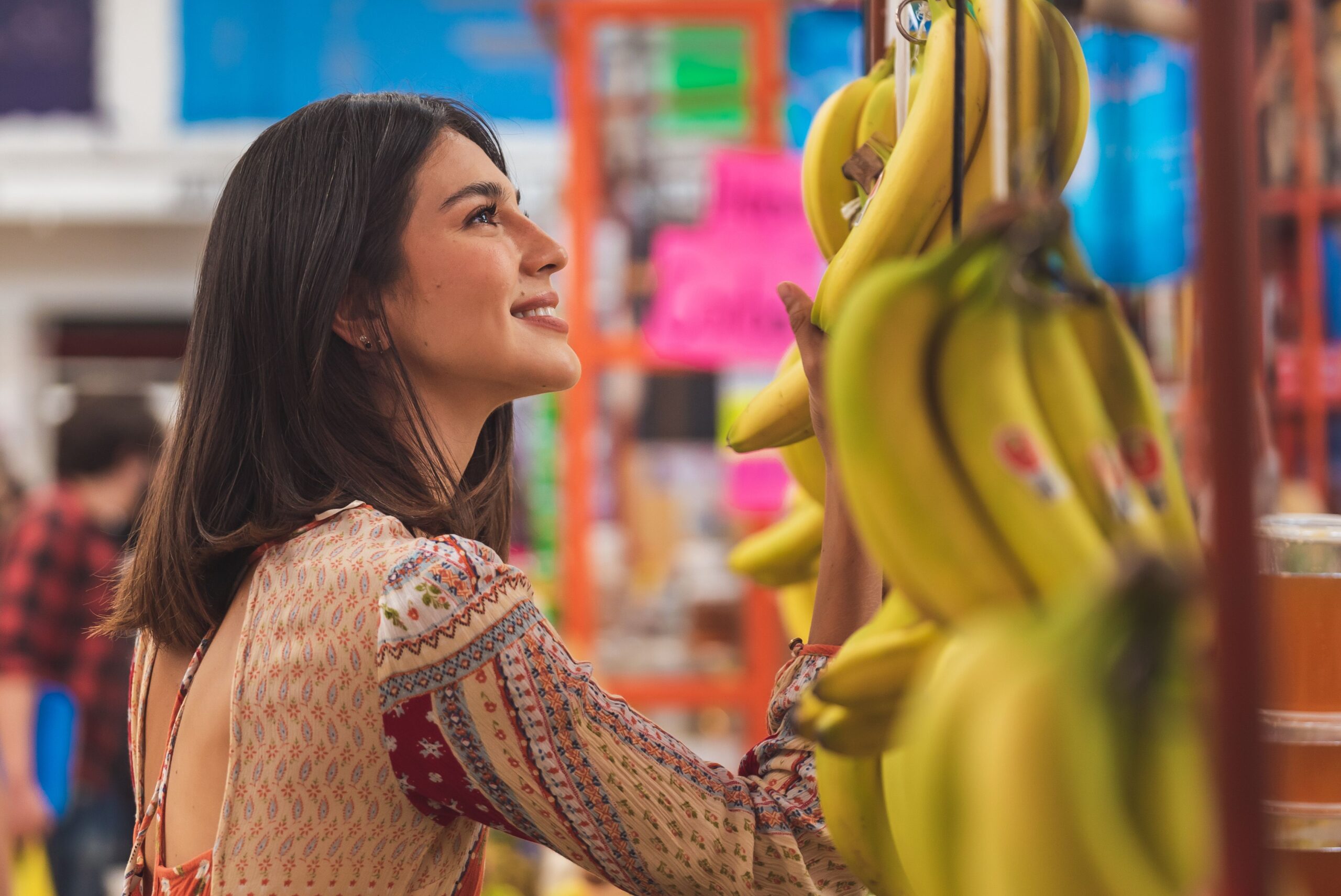 Lächelnde Frau greift im Supermarkt nach Bananen